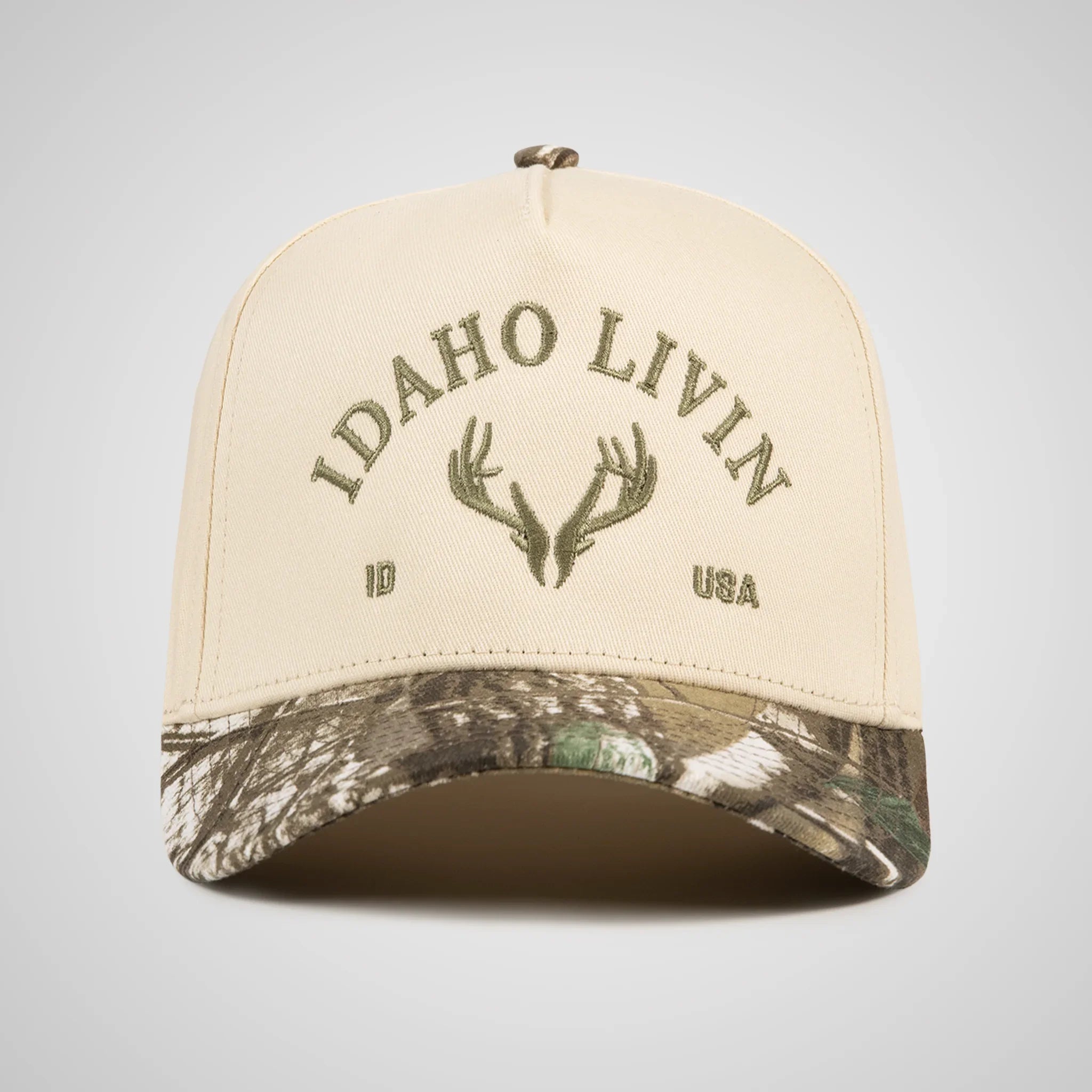 Beige and camouflage cap with 'Idaho Livin' and elk antler design on a gray background